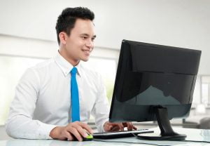IT Outsourcing Ausland. Ein Mann mit asiatischer Komplexion arbeitet an einem Computer.